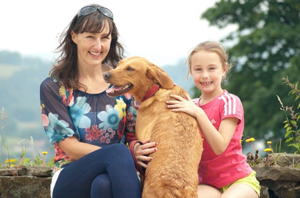 A host family relaxing outdoors with their boarding dog
